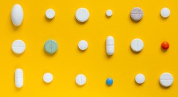 Medical white pills on a yellow background. Pharmaceutical concept