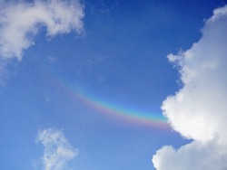 On cloud nine. Happiness concept. An arc of smiling rainbow in the blue sky, among white fluffy clouds. Smiley in the sky. Give hope. Have positive attitude, and be happy.                       