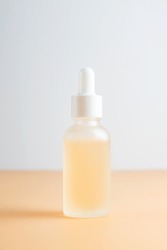 Side view of frosted glass dropper bottle with beauty face oil on beige background. anti aging serum with natural engredients