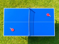 Aerial view blue table tennis or ping pong. Close-up ping-pong net. Close up ping pong net and line. Top view two table tennis or ping pong rackets or paddles  and ball on a blue table with net
