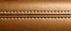 Car brown leather interior. Part of perforated leather door handle details. Orange Perforated leather texture background. Texture, artificial leather with stitching. 