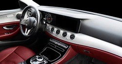 Red luxury modern car Interior. Steering wheel, shift lever and dashboard. Detail of modern car interior. Automatic gear stick. Part of leather seats with stitching in expensive car
