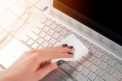 Woman cleaning computer keyboard. Female hands disinfecting laptop keyboard with antivirus wet wipes. Cleaning and disinfecting laptop computer with wet wipes