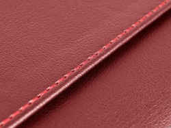 Red leather texture with red stitching. Part of perforated leather details. Red perforated leather texture background. Texture, artificial leather with diagonal red stitching.