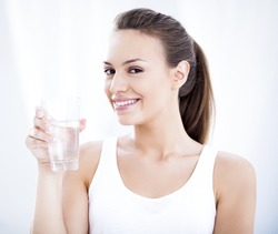 Studio shot of a young woman holding a glass of water.