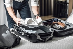 Hands of unrecognisable businessman packing his shirts in suitcase for business travel.