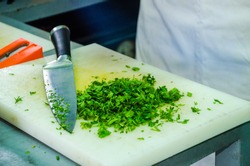 Chopped parsley on a white plastic cutting board wit the knife next to it