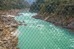 River rafting on the Ganga river in Rishikesh, Uttarakhand seen through a barbed wire fence on a briodge
