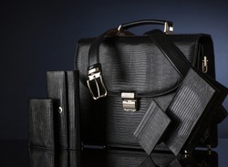 Fashionable men's set of leather accessories on a dark background. Briefcase, wallet, belt