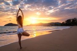 Summer woman vacations concept, Travel asia woman with white bikini and shorts jeans practicing yoga on sea beach in sunset at Koh Mak, Thailand