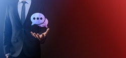 Businessman holding a message icon, bubble talk notification sign in his hands. Chat icon, sms icon, comments icon, speech bubbles.