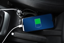 Mobile phone ,smartphone, cellphone is charged ,charge battery with usb charger in the inside of car. modern black car interior.