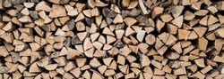 Background of stacked chopped wood logs. Pile of wood logs ready for winter. Wooden stumps, firewood stacked in heap 