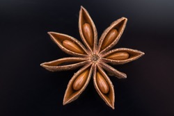 Star anise fruit and seeds on black acrylic background