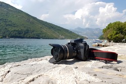 DSLR camera on the stone, in background is Lepetane, sea and mountains