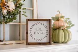 White mantel with modern stacked pumpkins and a sign that says hello fall