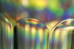 Light split into colours by a glass surface. Close up of glass with light interference effect, color diffraction. Transparent optical element that refract light.