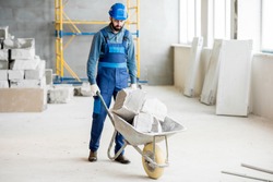 Builder carrying blocks on a wheelbarrow at the construction site indoors