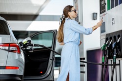 Woman paying with phone for gasoline, photographing bar code on the gas station pump