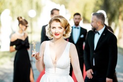 Portrait of a beautiful woman dressed in retro style as a famous movie actress on the red carpet during awards ceremony outdoors