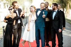 Group portrait of a famous movie actors standing together on the red carpet during awards ceremony outdoors