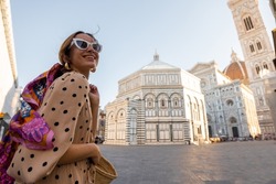 Woman enjoys beautiful view on famous Duomo cathedral in Florence, standing on empty cathedral square during morning time. Stylish woman visiting italian landmarks. Traveling Italy concept
