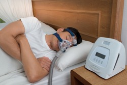 Happy and healthy senior man wearing Cpap mask sleeping smoothly all night long on his left side with cross arms without snoring, high angle view.Obstructive sleep apnea therapy.

