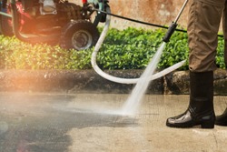 Worker cleaning driveway with gasoline high pressure washer splashing the dirt,professional cleaning services.High pressure cleaning,lower body.