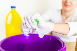 Detail of cleaning lady draining a wipe cloth with bleach in order to disinfect the house. Stay home concept and extreme hygiene protection against coronavirus covid-19 pandemic disease.