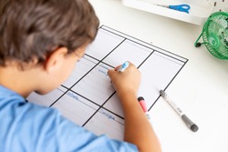 Child sitting at desk writing on weekly planner