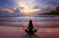 Beautiful woman doing yoga at the beach
