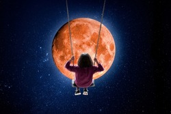 Girl swinging in front of the full moon
