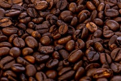 Coffee beans background. Grão de café. Fullframe shot of fresh roastend coffee beans zoom in. Aromatic brown textured seeds on background from close up. Black energy structured grain on backdrop. 