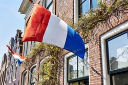 Dutch flags waving in the wind on the facade of typical dutch houses on Koningsdag. A national holiday in the Kingdom of the Netherlands.                  