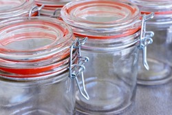 Closeup of empty glass canning jars or preserving containers with orange sealing ring in a row. Preserving food concept.            