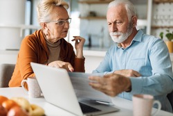 Frustrated senior couple sitting at home and  checking  their home finances