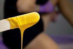 Melted depilatory wax. Shugaring with hot wax. The wax flows over the spatula. Hair removal with wax. The girl removes her hair.