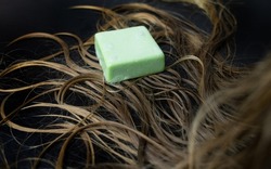 Solid hair shampoo. Composition of golden curls, soap suds, solid shampoo and comb. The concept of female care for long hair.