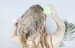 Solid hair shampoo. Close-up of a blonde girl in the bathroom, which lathers her hair with dry shampoo. Lots of foam and peek effect.