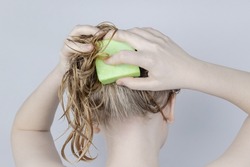 Solid hair shampoo. Close-up of a blonde girl in the bathroom, which lathers her hair with dry shampoo. Lots of foam and peek effect.
