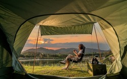 Asian woman travel and camping alone at natural park in Thailand. Recreation and journey outdoor activity lifestyle. Good morning and fresh start of the day.