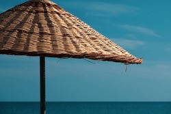 A retro beach umbrella in retro colors in front of a navy blue sea on an empty beach. Summer beach concept.