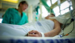 Doctor comforting a patient in an intensive care unit in a hospital