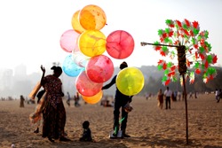 A Balloon and Toys and Windmill Seller on a Beach in India with Colorful Balloons and Windmills with Vendor in Silhouette