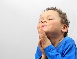 boy praying to God with hands held together with closed eyes stock photo