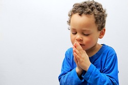 little boy praying to God stock image with hands held together with closed eyes with people stock photography stock photo
