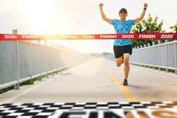 Excited man runner crossing the 2020 finish line of marathon. 2020 success concept