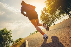 Young woman running sprinting on road. Fit runner fitness runner during outdoor workout with sunset background.	