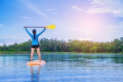 Young woman have fun on stand up paddle board. Active paddle boarder paddling at the lake. Water sport, SUP surfing tour in summer holiday vacation.