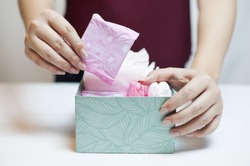 Closeup photo of young woman picking sanitary pad out of green box